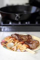 Surf and turf with NY strip and shrimp kabobs with grilled onions, on a plate next to the stove.