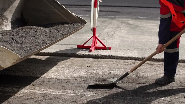 Workers remove shovels old cut asphalt from the road for laying new asphalt. Preparation of the road for laying new asphalt.