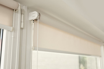 Window with modern roll blinds in room, closeup