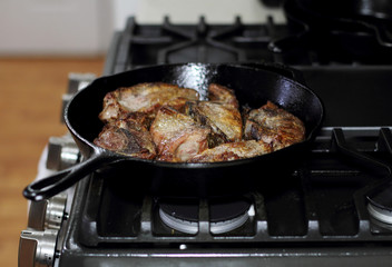 Country style cut pork ribs in a cast iron pan on the stove top.