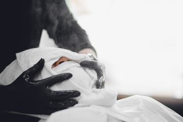 Barber steam face skin of man with hot towel before royal shave in Barbershop