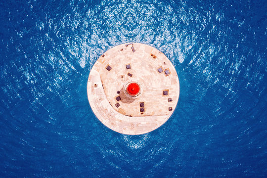 Red Lighthouse Against Blue Water Of Sea. Contrast Colors. Top Aerial View