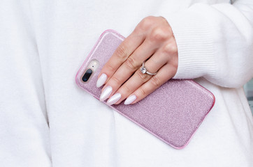the female hands engagement ring in the sweater is holding a  smartphone in glitter case. A...