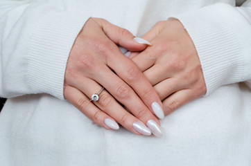 the female hands with beautiful professional manicure engagement ring in the sweater on a pregnant belly.