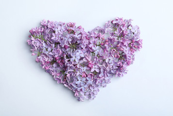 Heart made of blossoming lilac on light background, flat lay. Spring flowers