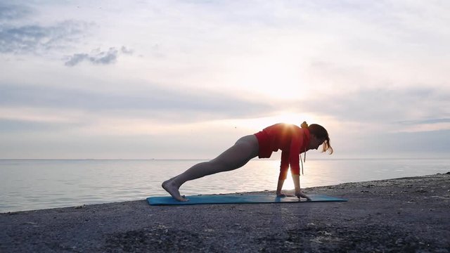 Silhouette of female making eka pada adho mukha svanasana pose in hatha yoga asana at sunrise
