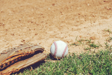 Baseball with old glove on sports field closeup.