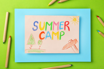 Paper with written text SUMMER CAMP, drawings and different pencils on color background, flat lay