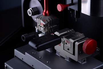 Close view of key copying machine with key. Duplicate machine make new key. Locksmith theme. Blank keys for cutting. Black modern car door opener.