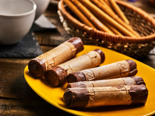 Cookies sweet food on breakfast. Crispy wafer rolls with cream served cups and plate on wooden table in country style.