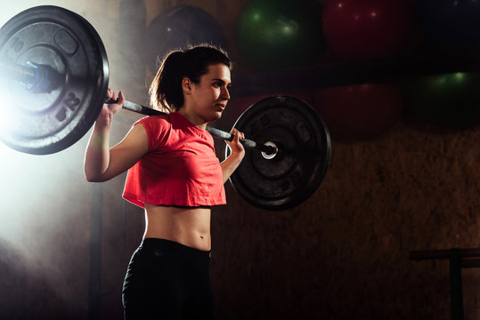 Fit young woman lifting heavy weights at gym