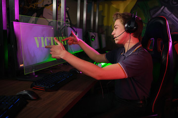 Professional young caucasian gamer playing online on his PC. He upset because of losing the game