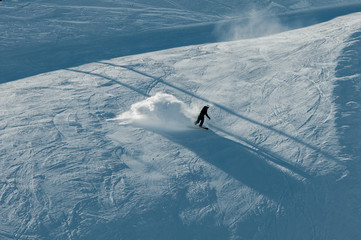 A snowboarder making a snow cloud on the slope