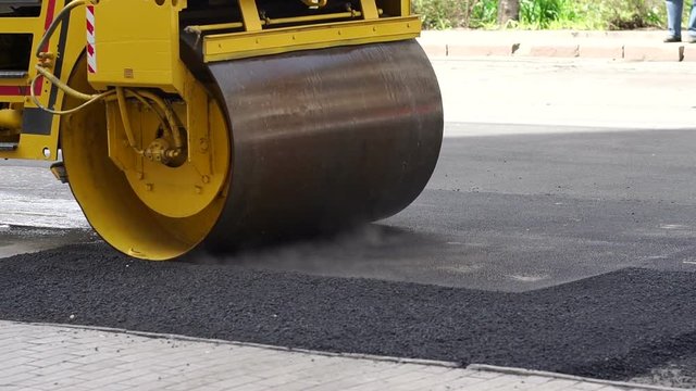 Industrial landscape with rollers that rolls a new asphalt in the roadway. Repair. The large working machine of the skating rink makes a new asphalt.