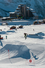 A snowboarder hitting his jump off the kicker in the snowpark