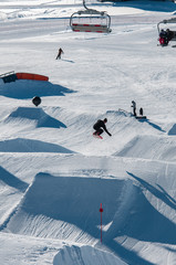 A snowboarder hitting his jump off the kicker in the snowpark