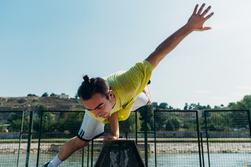 Sportive guy practicing parkour exercise in skatepark