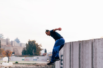 Caucasian man trains parkour while jumping over a high top.