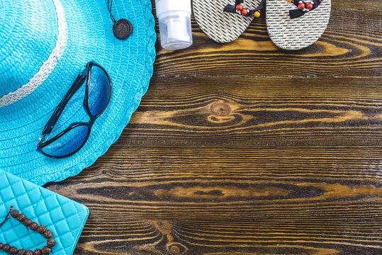 Travel holiday supplies: hat, sunglasses, flip flops, passport and airline tickets on old wooden background. Top view