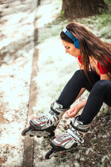 Beautiful girl is prepairing for rollerblading at the street