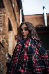 beautiful brunette in a plaid jacket at the brick wall - 270457412