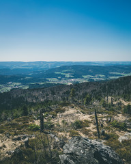 View from the top of a mountain into the valley with clouds in the blue sky and beautiful green...