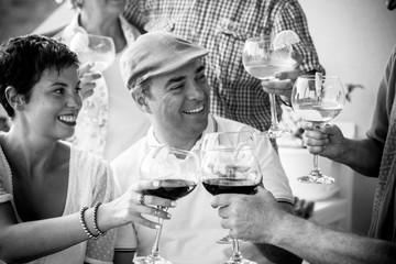 Black and white friendship people concept with couple and friends together toasting and cheering with wine red and cocktails - celebration concept  with caucasian man and woman