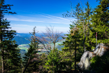 View from the top of a mountain into the valley with clouds in the blue sky and beautiful green...