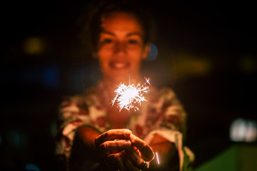 Celebration and happiness concept with cheerful woman with sparkler fire by night - new year eve motivational image - romantic and romance love atmosphere with red colors and feeling
