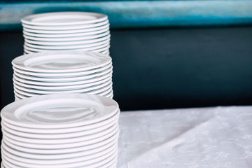 Obraz premium Pile of white clean dishes on a table - close up of kitchen stuffs for catering or restaurant business concept