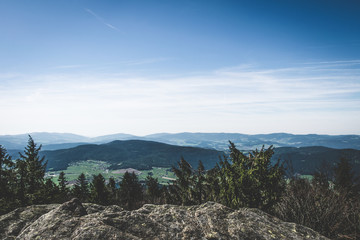 View from the top of a mountain into the valley with clouds in the blue sky and beautiful green...
