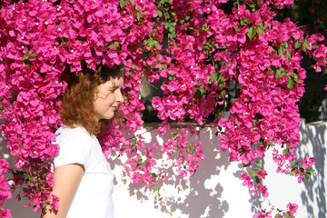 Girl among pink flowers in sunlight