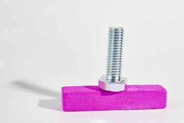 the metal bolt with thread lies on a wooden bar