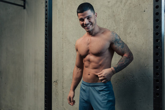 Young Strong Man In Gym Pinching His Abdomen Fat