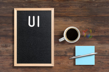 letter board with acronym UI on wooden background