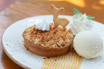 Classic crispy apple crumble with vanilla ice cream fresh whip cream and animal biscuit in beautiful plate.  Pastries crispy desert.