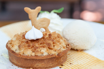 Classic crispy apple crumble with vanilla ice cream fresh whip cream and animal biscuit in beautiful plate.  Pastries crispy desert.