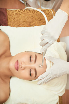 Asian young woman lying on treatment table and getting laser therapy in spa salon