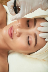 Close-up of beautiful woman getting rid of wrinkles with special laser equipment during spa treatment in beauty salon