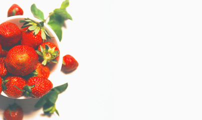 White bowl with fresh red strawberries and mint on a light  background close up.  Healthy food ingredients theme concept. Top view