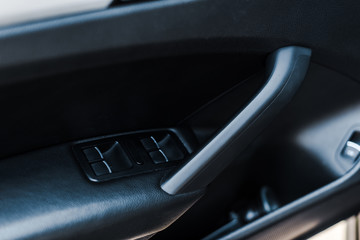 black automobile door handle near buttons in modern car
