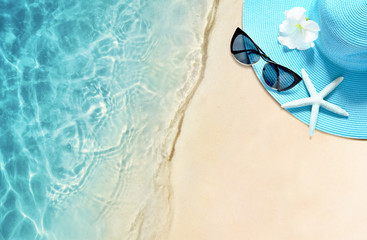 Hat and sunglasses on the sandy beach. Summer background