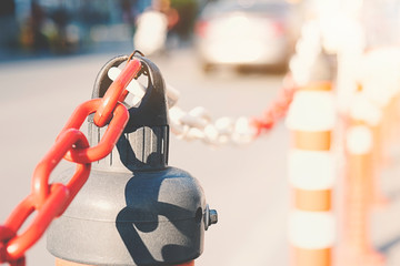 Traffic cones have a chain. Traffic pole white and red have chains