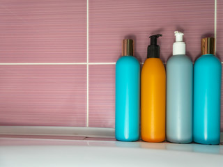 Plastic bottles of various colors with detergent, shower gel, shampoo on the bathroom. Domestic life concept, comfort, order, close up, copy space