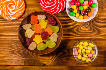 Different sweet candies on a wooden table. Top view