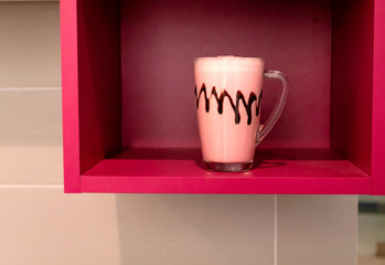 Cold pink milkshake in glass mug on pink background. Minimalism.