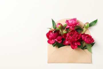 Beautiful peony flowers in envelope on white background, space for text