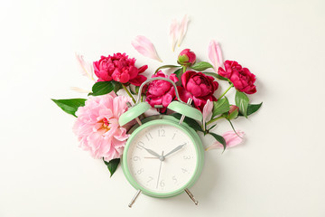 Flat lay composition with beautiful peonies and alarm clock on white background, space for text