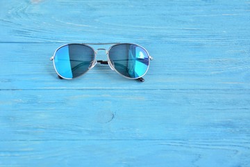 Colorful aviator eyeglasses with selective focus on textured blue background. Summer vacation concept with stylish eye glasses. Blue wooden table with fashionable eyes accessory. Sun protection