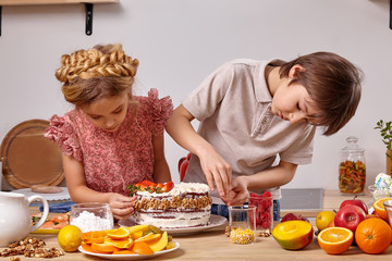 Little friends are making a cake together at a kitchen against a white wall with shelves on it.
